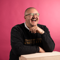 A person in a black sweatshirt against a reddish background